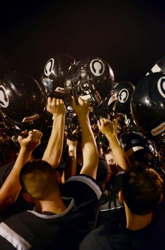 In a huddle, the Centralia Panthers lift their helmets after a