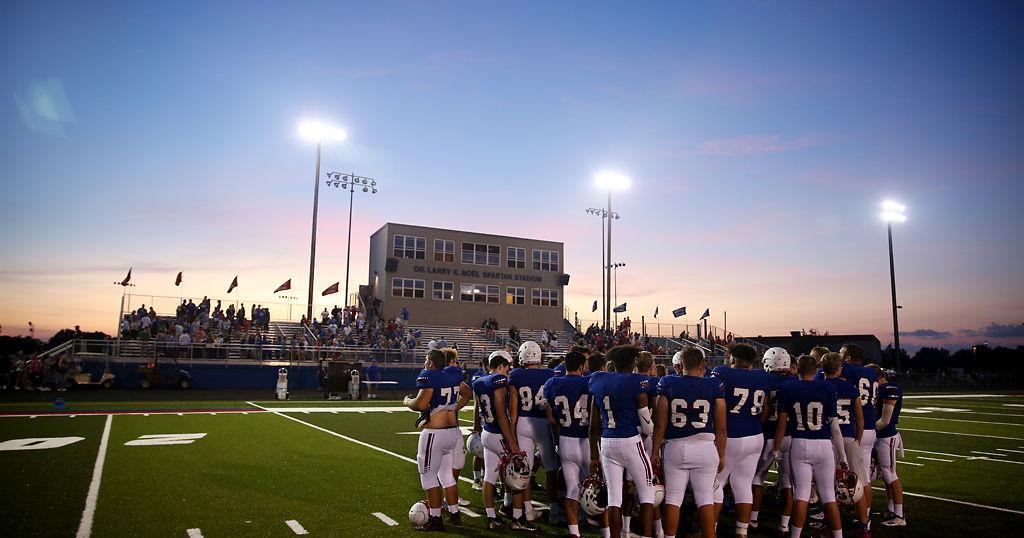 The Moberly High School football team talks in a huddle after the