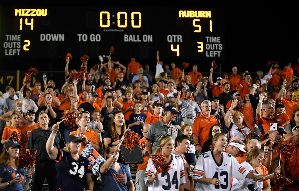 Auburn fans cheer beneath a scoreboard showing the final score of the