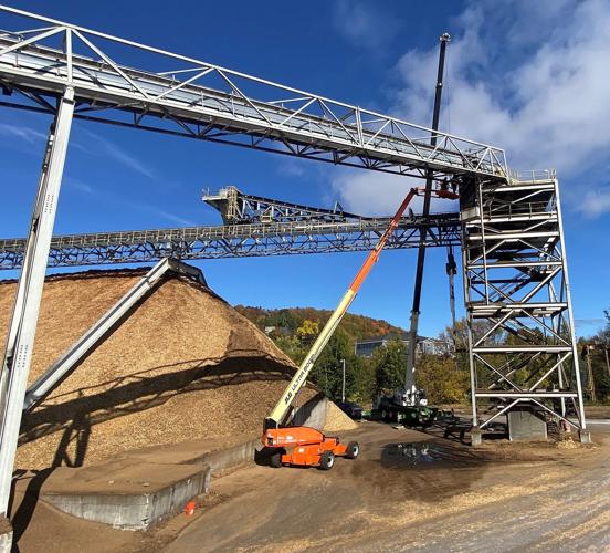 Burgess BioPower workers perform maintenance on the conveyer system.