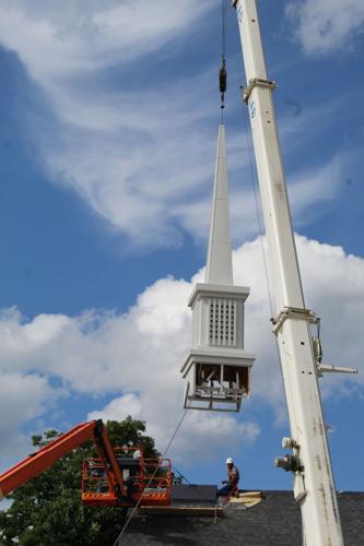 A crane lifts the new steeple atop Holy Family Church