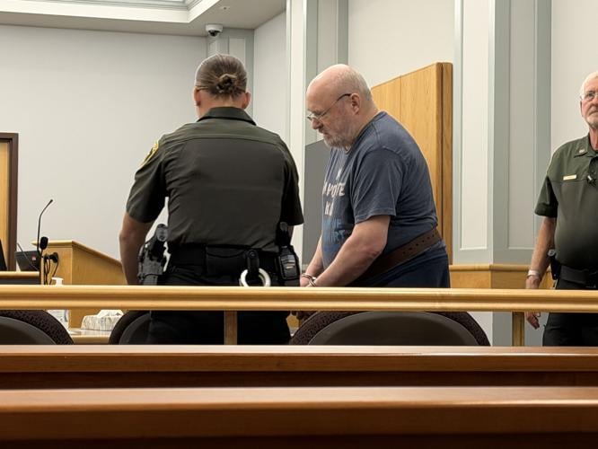 Richard R. Devoid is guided into a Coos County Superior courtroom