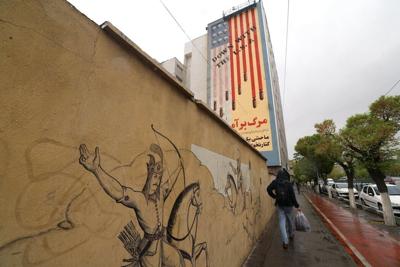 An Iranian walks past an anti-U.S. mural in Tehran on April 5, 2025.