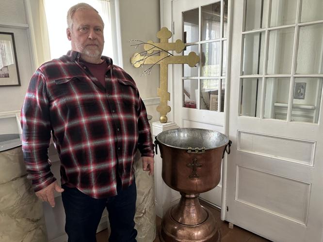 Mark Tupick stands in front of the copper baptismal font