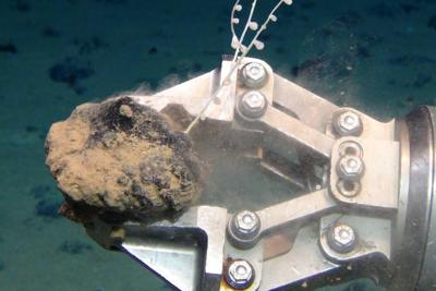 A mechanical claw holds a polymetallic nodule, one of several seafloor sources of critical minerals.