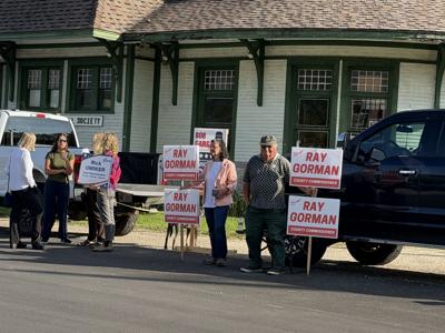 Campaigners hold signs in Gorham on Sept. 8, the state primary election day