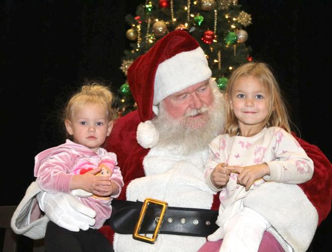 Visiting with Santa Claus are (from left) Elsa and Piper Simmons