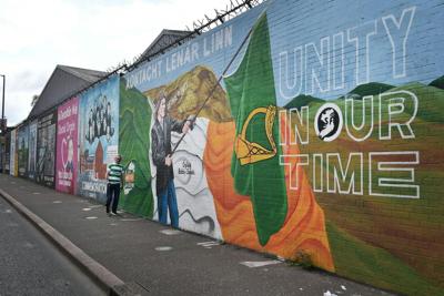 A man walks past a mural calling for Irish unity in Belfast, Northern Ireland.
