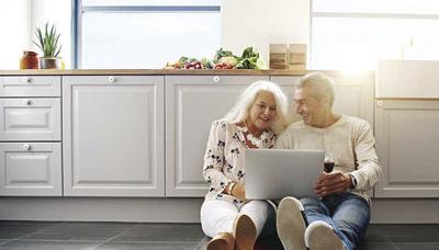 Senior people using laptop in kitchen.