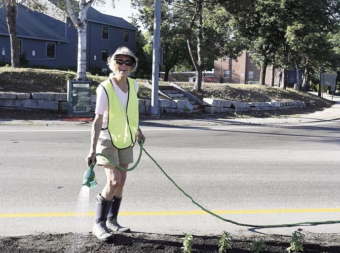 Margaret Marshall waters flowers on the traffic islands