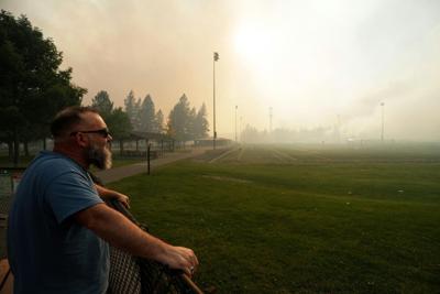 Andrew Rowley watches a wildfire burning from a distance after evacuating his home on Aug. 1, 2026, in Spokane, Wash.