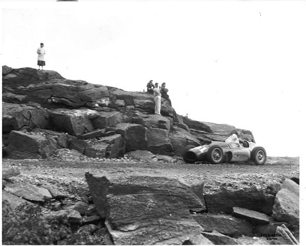 1956 racecar driving by rocks and people