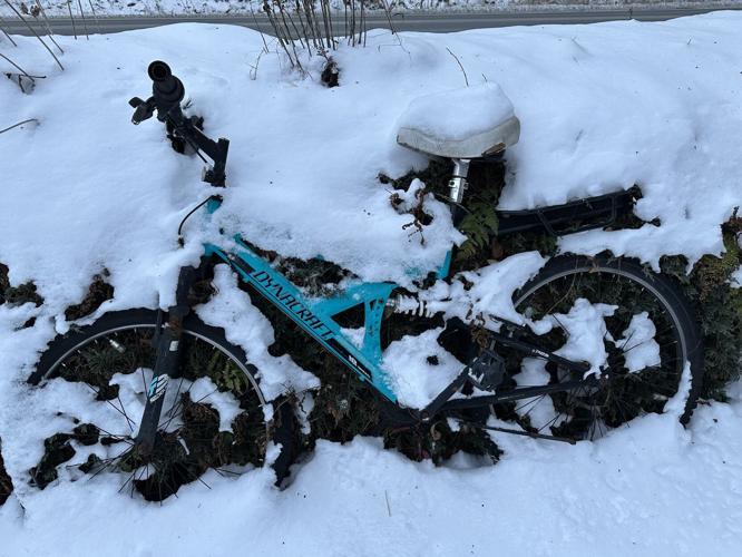 A snow-covered bike leans against a wall in Gorham