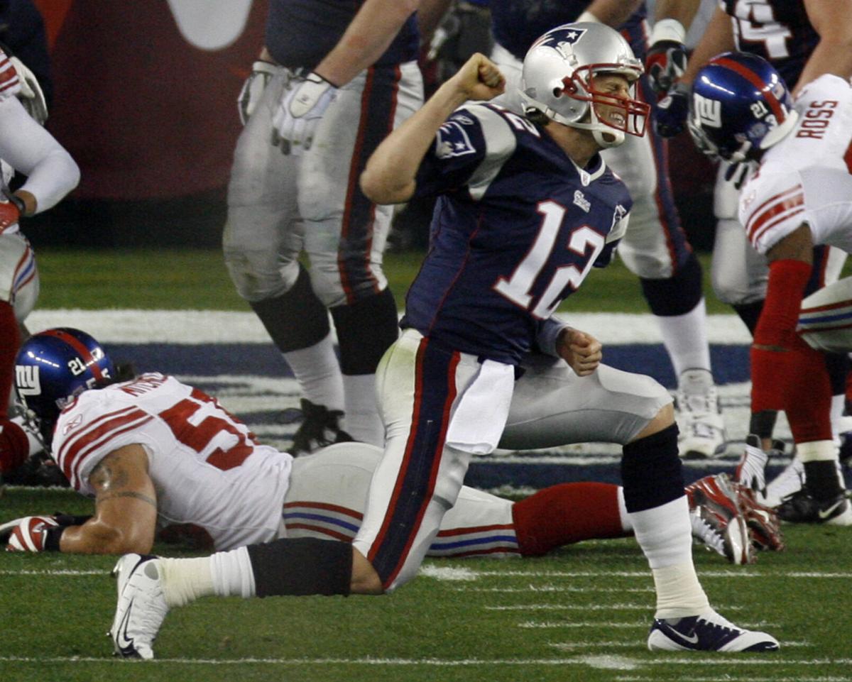 FILE - In this Feb. 3, 2002, file photo, New England Patriots players reach  out to touch the Vince Lombardi Trophy after the Patriots defeated the St.  Louis Rams 20-17 to win