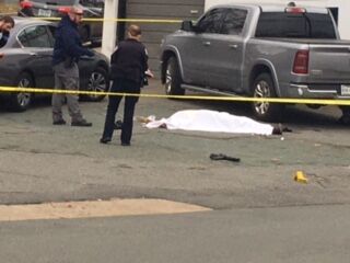A gun can be seen near a body of a deceased person Sunday afternoon