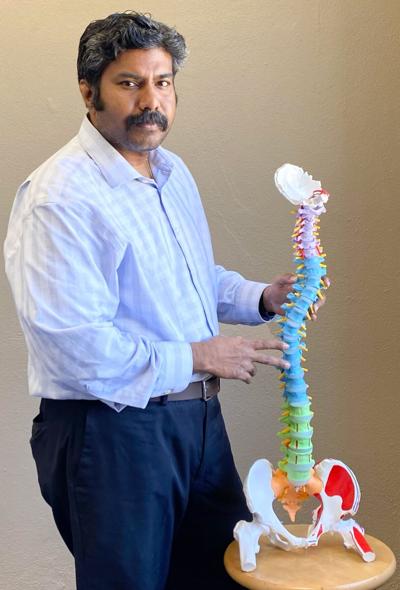 Balasubramanian poses alongside a skeletal scoliosis model