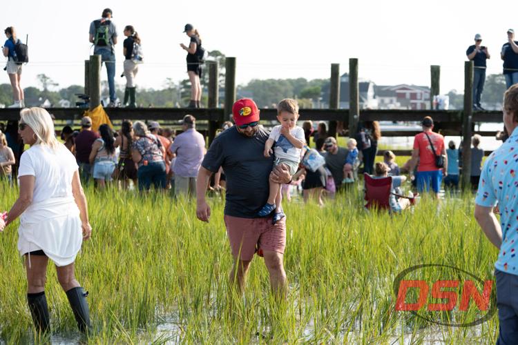 Man carrying a toddler through the crowded marsh.jpg