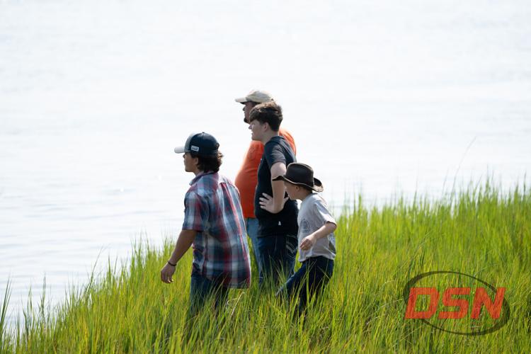 Boy in a cowboy hat walking with family through the marsh grass.jpg