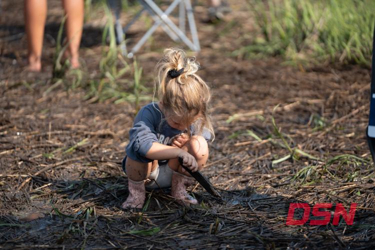 Little girl crouching down playing in the mud.jpg