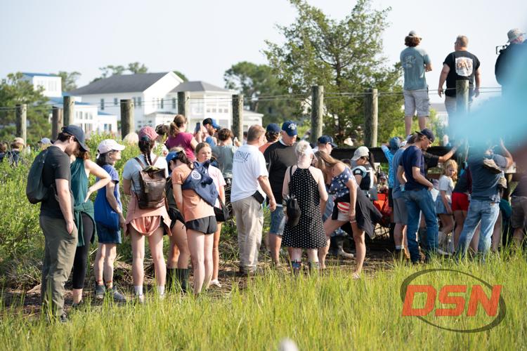 Crowd of spectators gathered along the fence rail.jpg