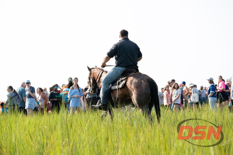 Saltwater Cowboy riding away from the crowd through the marsh grass.jpg