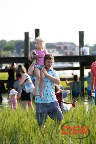 Man carrying a girl on his shoulders through the marsh grass.jpg