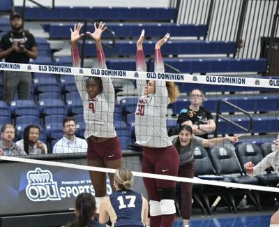 University of Maryland Eastern Shore players jump vertically near the net in maroon and gray uniforms.