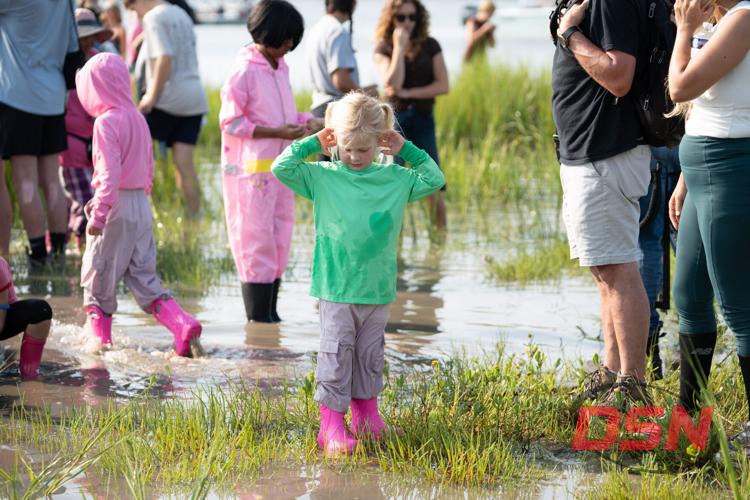 Girl in pink boots covering her ears in the marsh.jpg