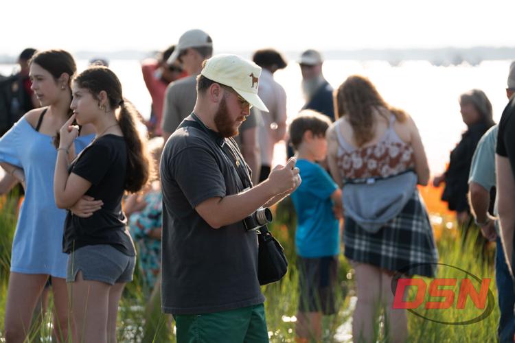 Man in a pony hat taking a photo with his phone.jpg