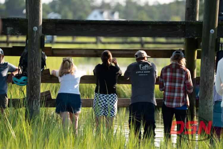 Spectators leaning on the fence rail watching the water.jpg
