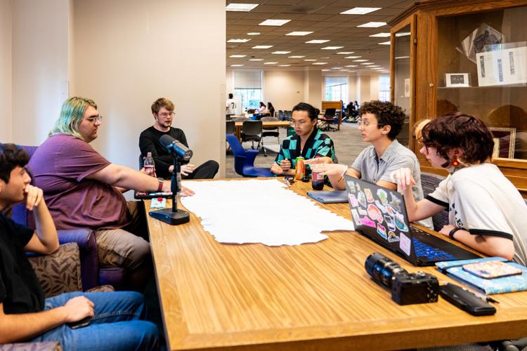 Six people sit at a big wooden table.