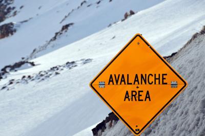 Avalanche sign against snow covered slope Photo Credit: mtcurado (iStock).