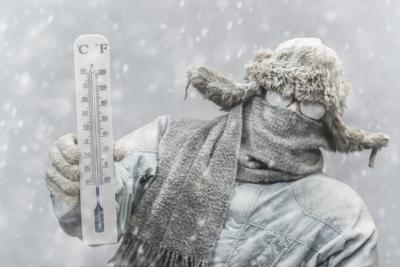 Frozen man holding a thermometer while it is snowing Photo Credit: cmannphoto (iStock).