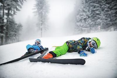 Little skiers lying on slope after crashing Photo Credit: Imgorthand (iStock).