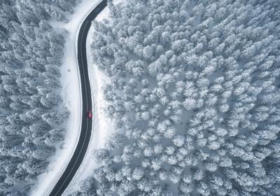 Driving In Snowcapped Forest Photo Credit: borchee (iStock).
