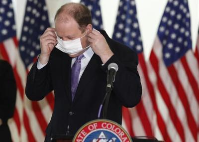 Jared Polis dons a mask. The Associated Press.jpg