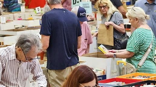 People browsing through a massive collection of books at local library sales