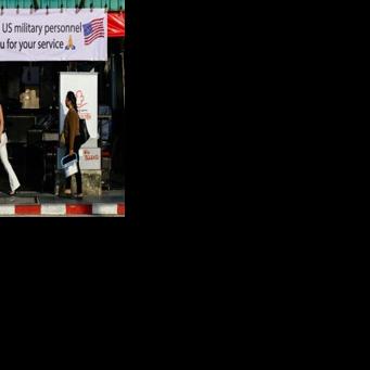 Pedestrians walk past a banner welcoming US military personnel displayed outside a bar in Pattaya