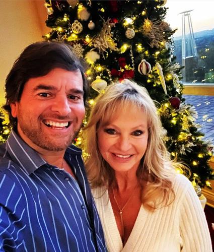 A couple, David Lieber and Heather Winfield, in front of a Christmas Tree