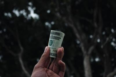 Person holds up wad of dollar bills to symbolize money lending