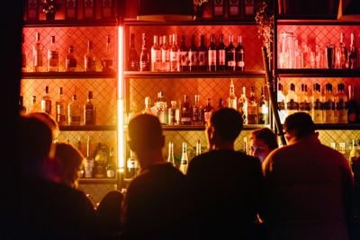 People hover around backlit bar