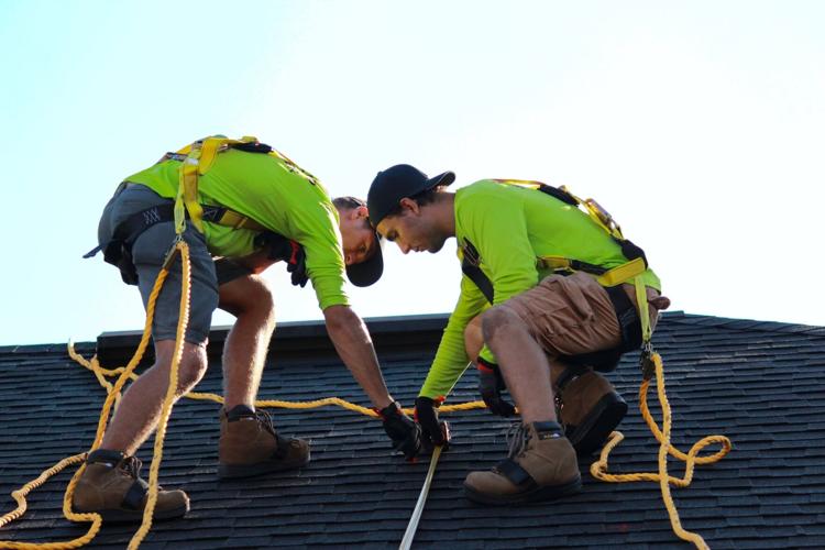 Two workers fix a roof using various tools
