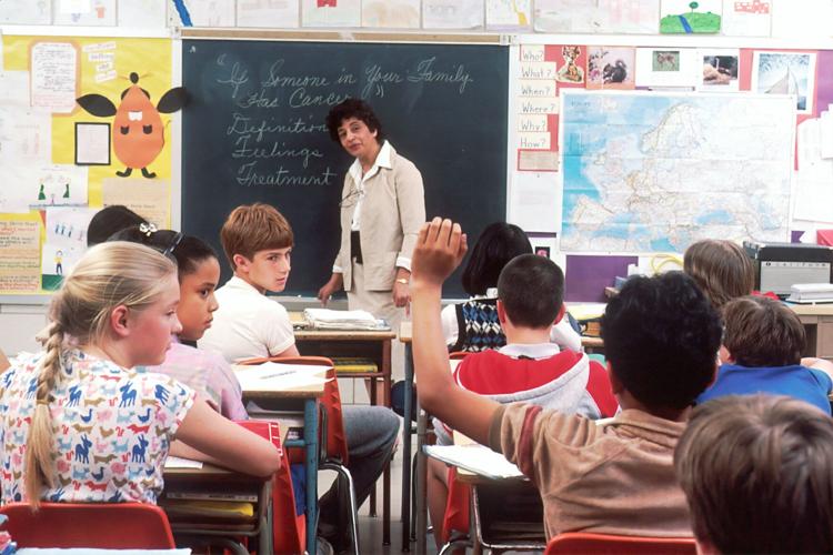 Children sit in a classroom covered in educational signs
