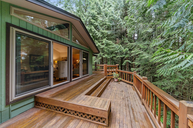 a beautiful wraparound deck in a wooded backyard
