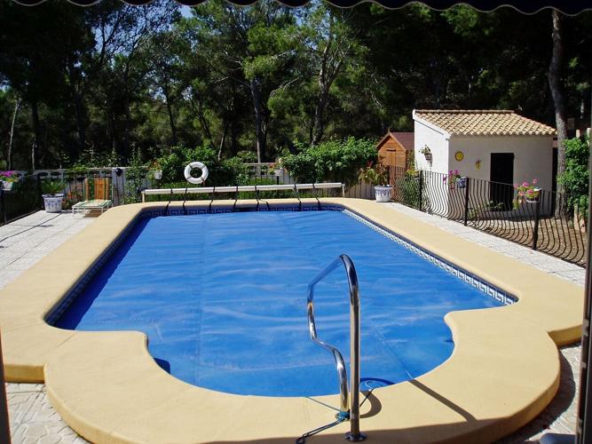 A backyard pool with a pool cover to help protect the pool and water quality