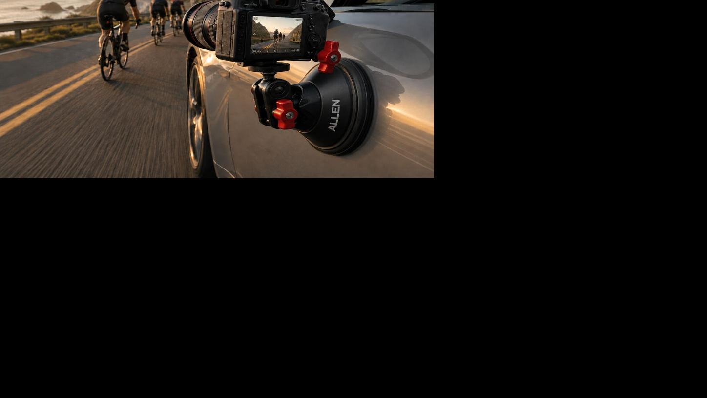 Camera securely mounted to a vehicle while filming a scenic coastal road trip with cyclists traveling nearby.