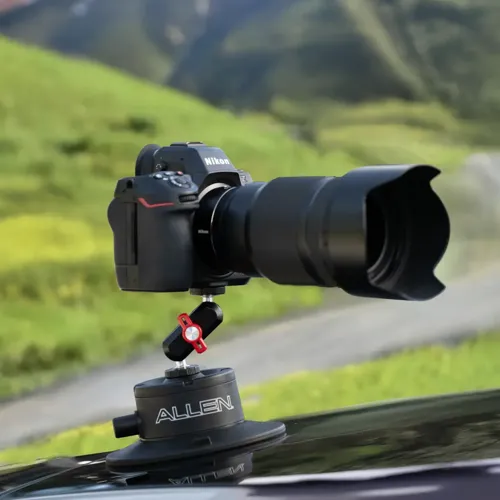 Camera securely mounted to a vehicle while filming a scenic coastal road trip with cyclists traveling nearby.