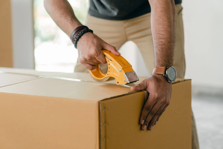 man taping carrying box with scotch