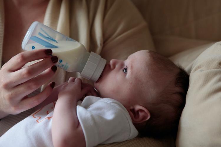 Mother feeds her baby milk from a bottle