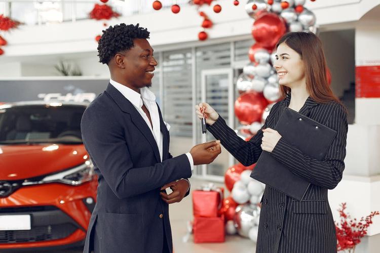 Car salesperson hands over keys to luxury car to buyer